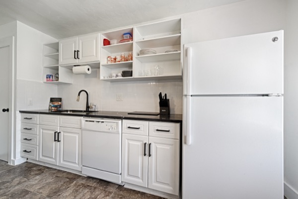 Renovated white kitchen with black quartz counters, full-size refrigerator and dishwasher