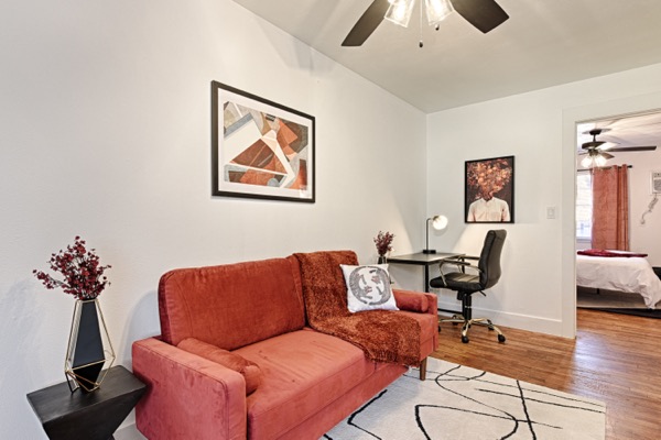 Living room with terracotta sofa, framed art and ceiling fan