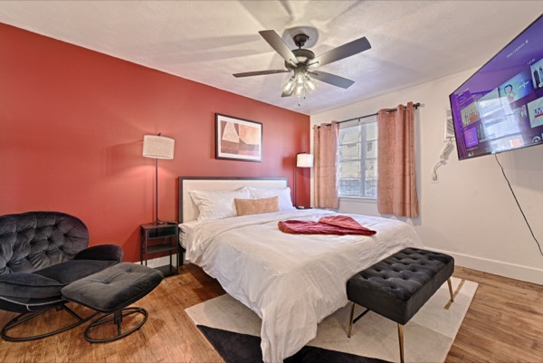 Bedroom with king bed, accent wall, reading chair and bench