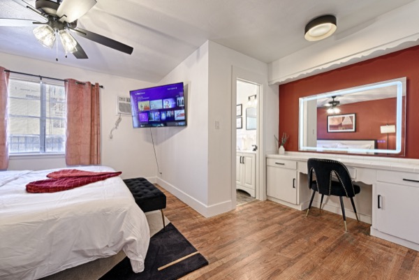 Bedroom with wall-mounted TV looking toward the bathroom