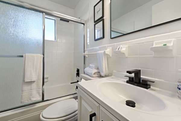 Renovated bathroom with tub-shower, white tile and black fixtures