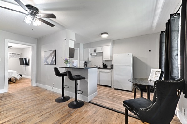 Refreshed unit wide view showing kitchen, dining seating, and bedroom beyond
