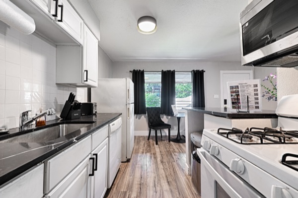 Refreshed unit galley kitchen with black curtained window and dining chair beyond