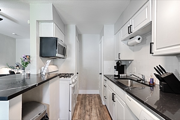 Refreshed unit galley kitchen viewed down the hallway toward the bedroom and bath doors